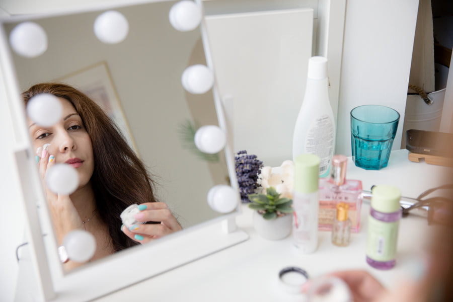 Woman looking into a mirror while rubbing in face cream
