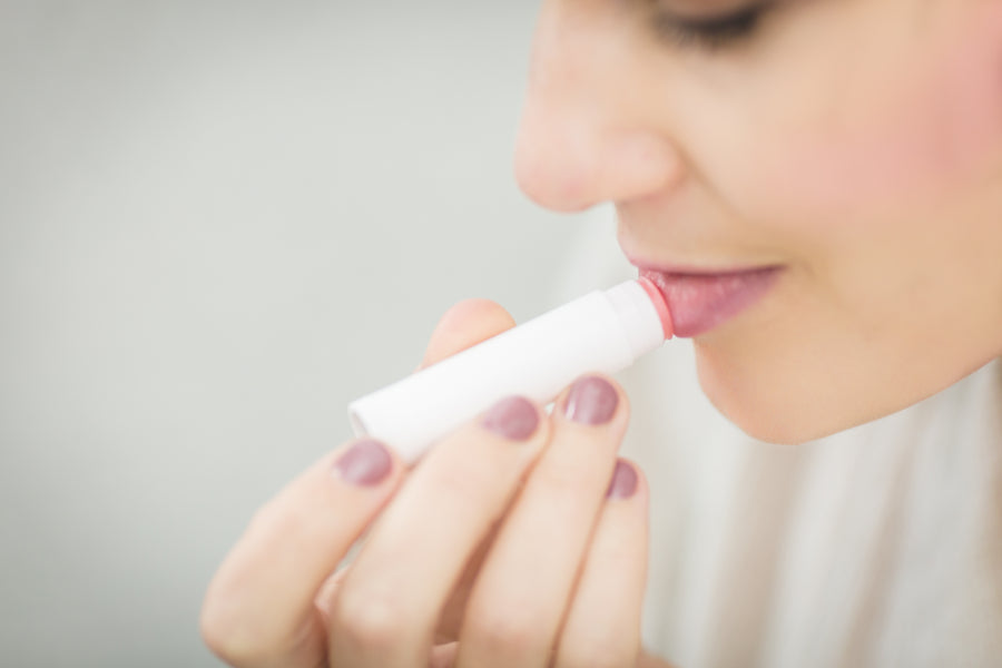 Woman applying a white lip balm stick