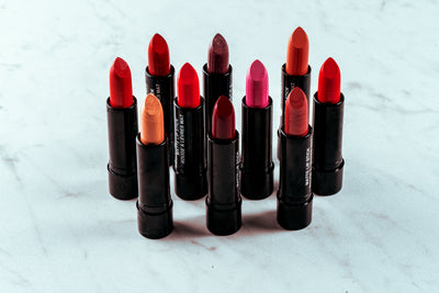 Collection of red and nude shade lipsticks standing on a marble surface