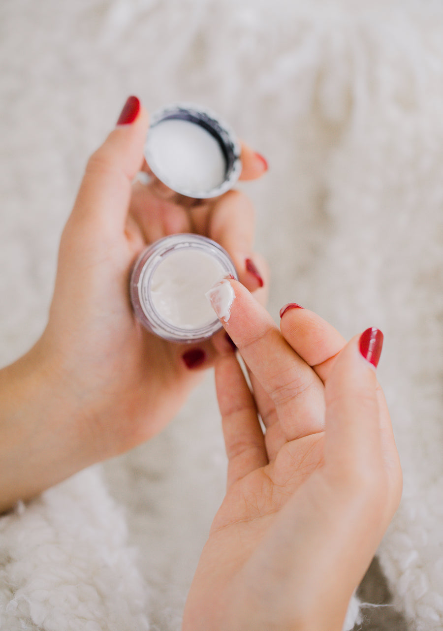 Hands holding a small cosmetics cream container