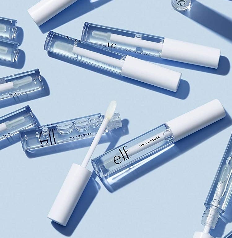 Clear lip gloss tubes arranged on a light blue background