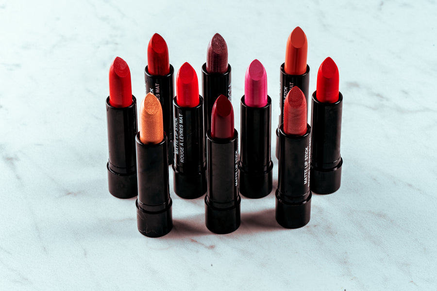 Collection of red and nude shade lipsticks standing on a marble surface