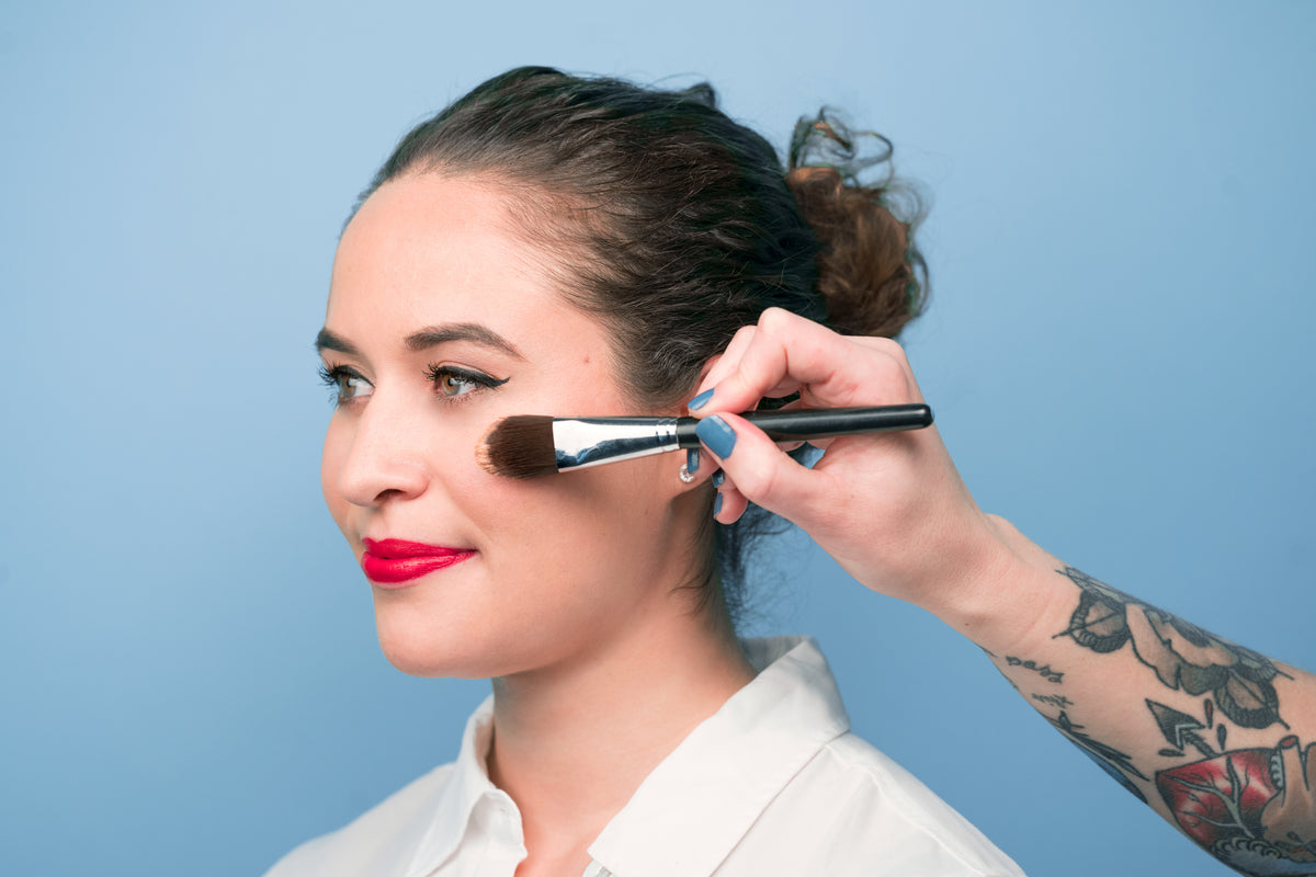 Makeup artist working on a model in a bright studio