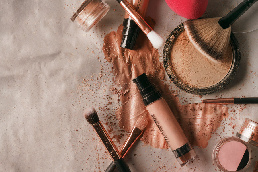 Face makeup products including foundation, powder and brushes on neutral fabric